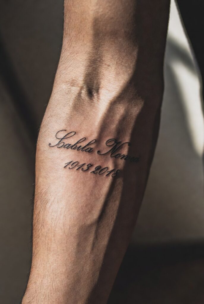 "Memorial tattoo ideas for men featuring name, dates, and script design honoring a lost loved one"