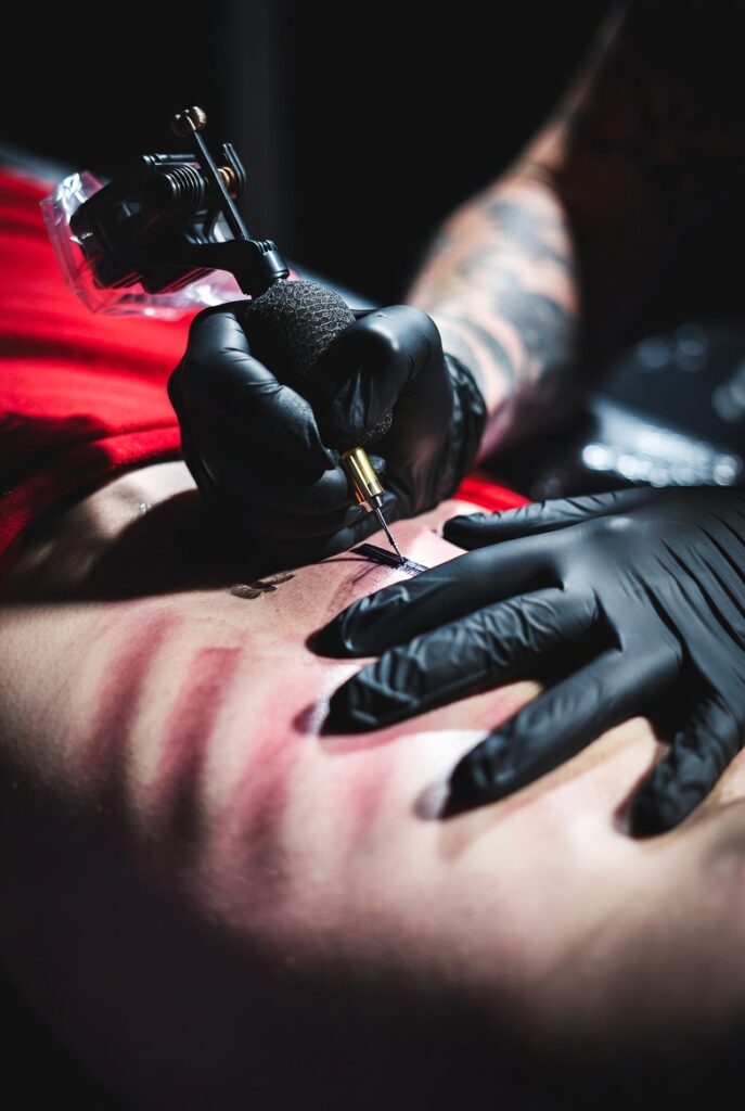 Tattoo artist inking a client's ribcage, illustrating the most painful body parts to get tattooed and how to survive them"